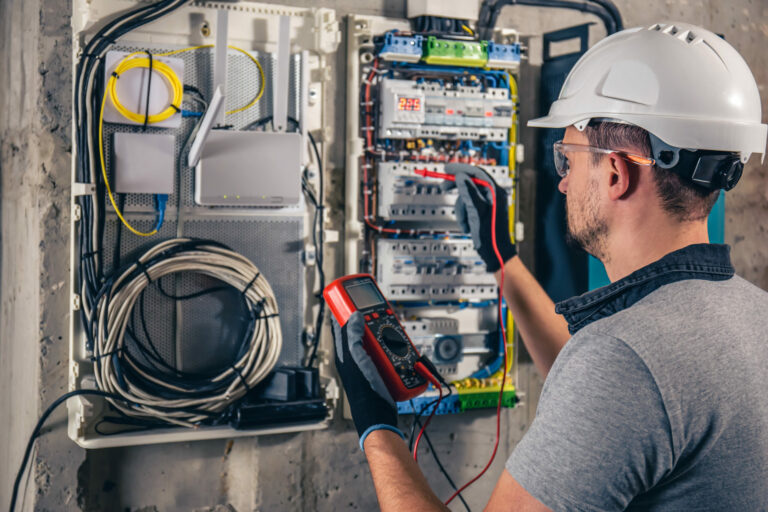 Elektriker installiert Sicherungskasten und prüft Leitungen in einem Neubau.